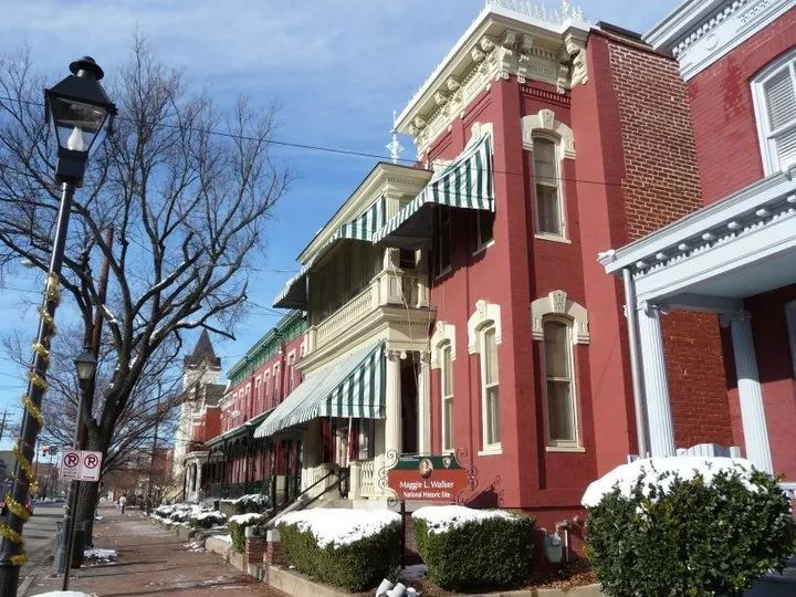 Red brick Victorian home with white and green awnings in the winter