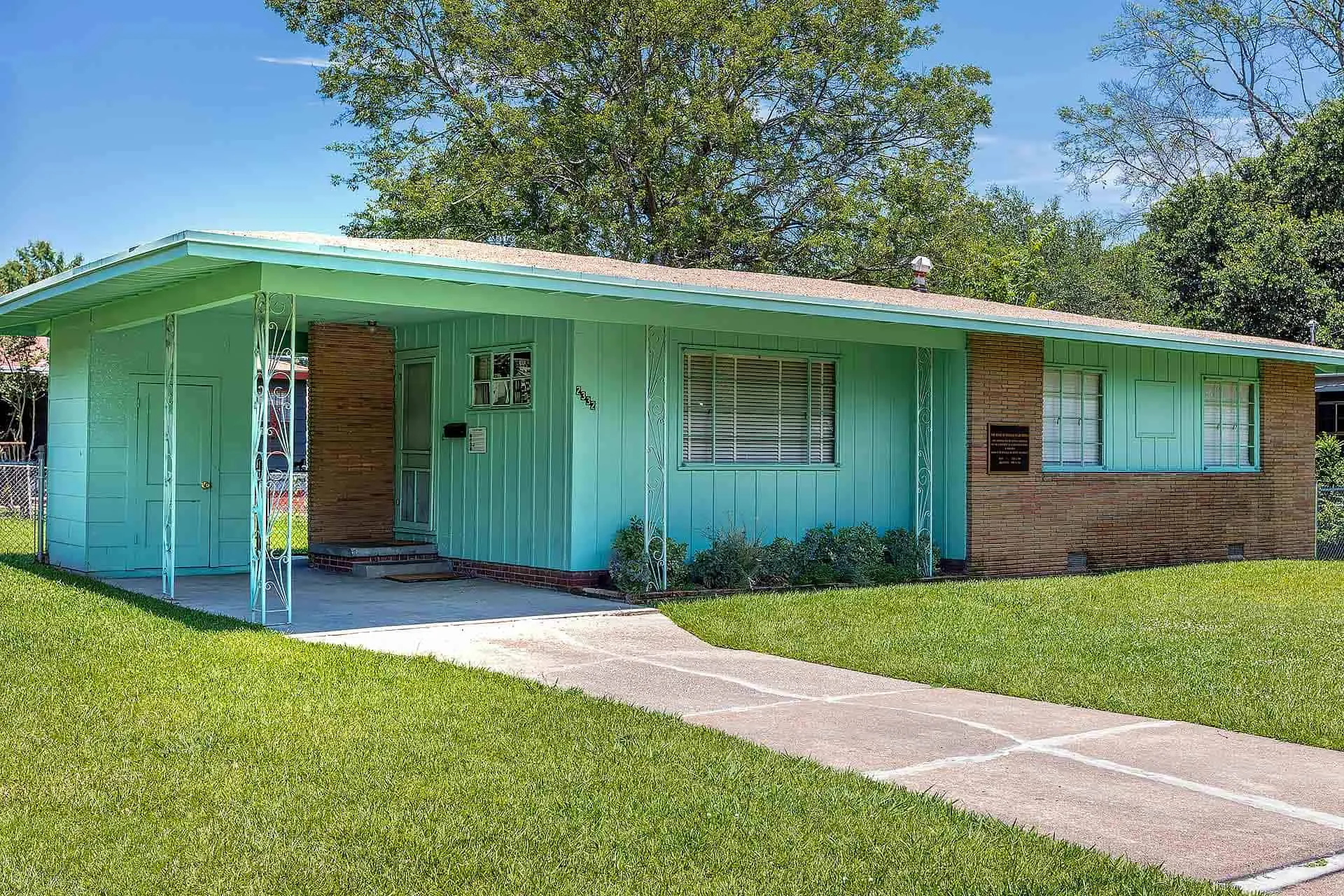 A single-story ranch-style house with light brown brick and teal siding.