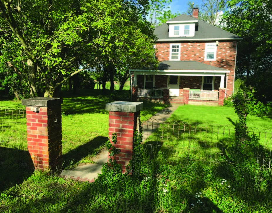 A paved path leads up to a two-story brick house