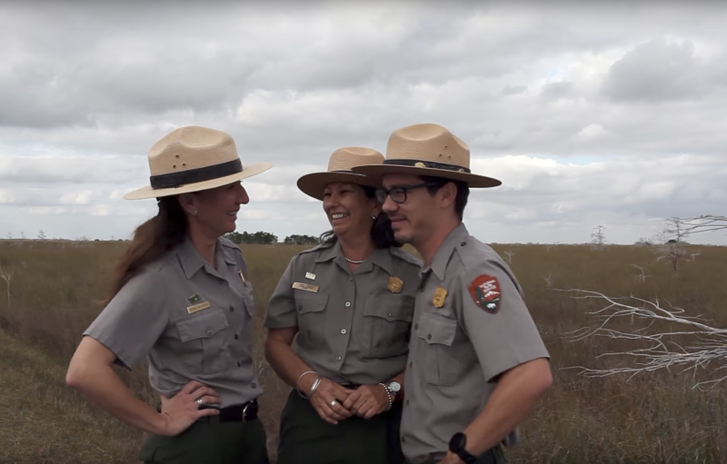 Three park rangers chatting and laughing in the middle of the prairie