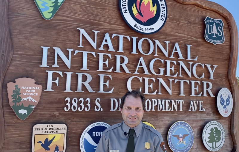 Bill Yohn poses in front of the sign at the National Interagency Fire Center
