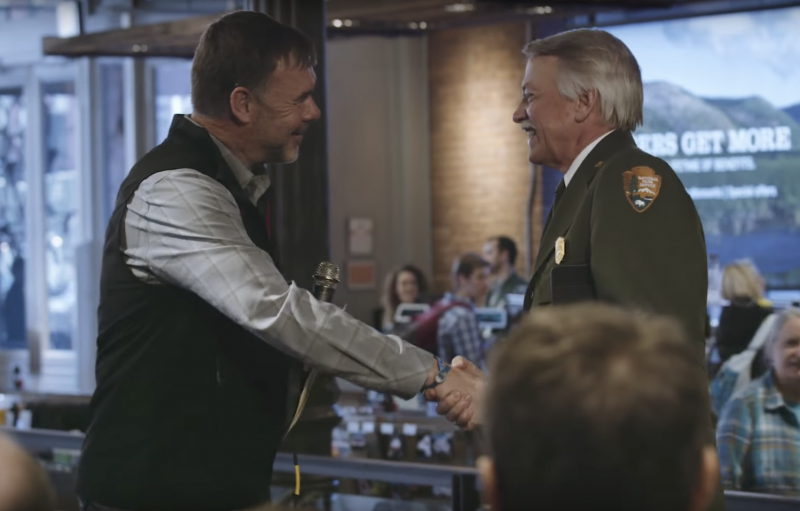 An REI employee shaking hands wit the former National Park Service Director John Jarvis
