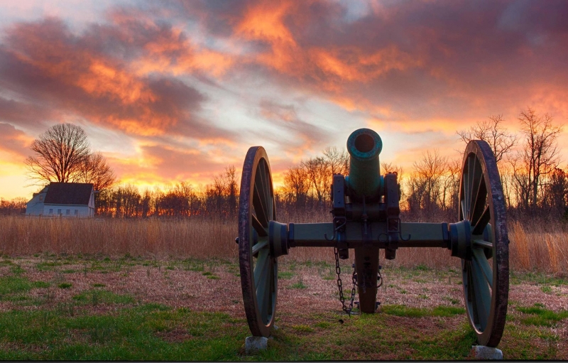cañón contra la puesta de sol en el campo de batalla