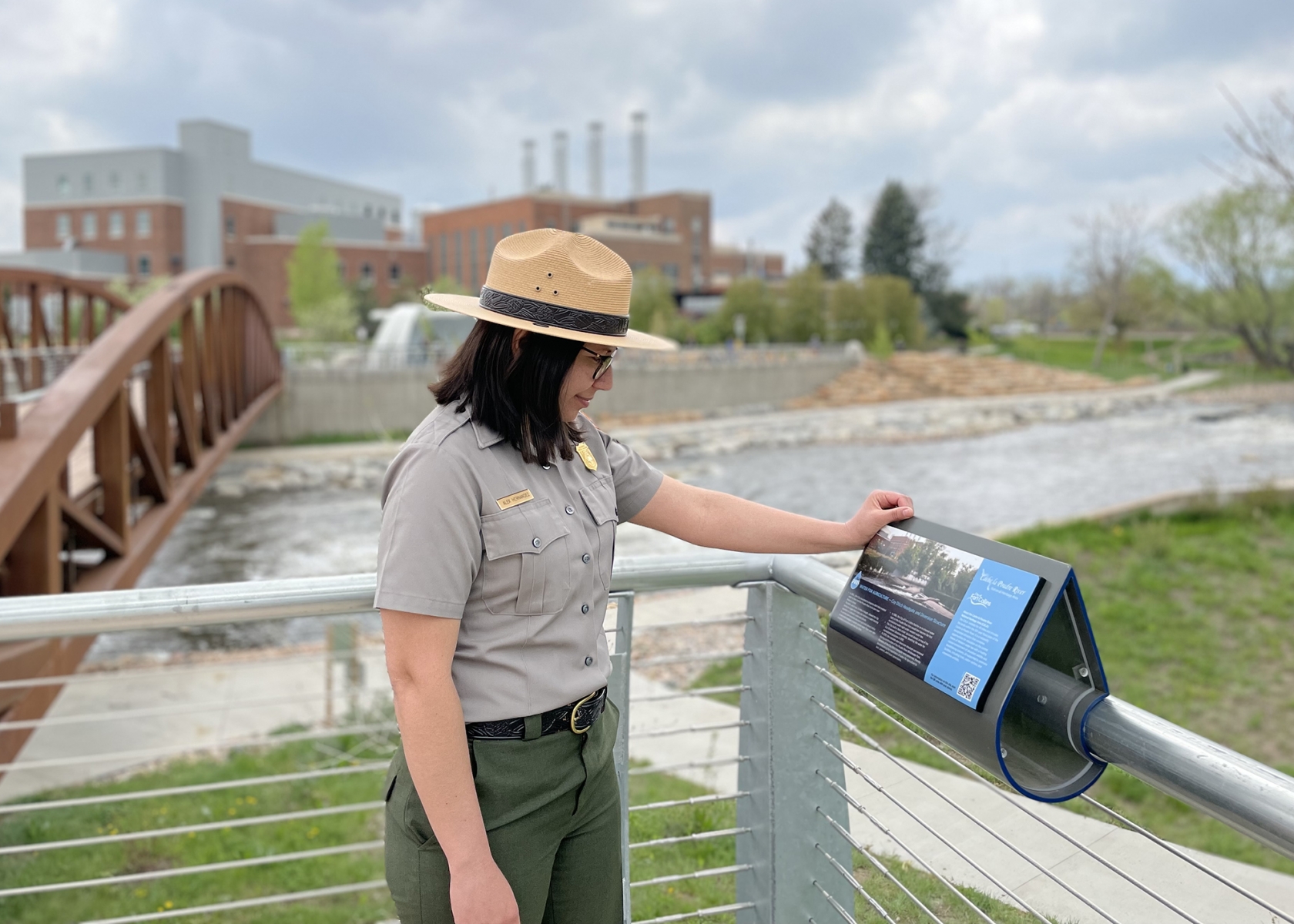 Alex Hernandez stands by a wayside exhibit along a river