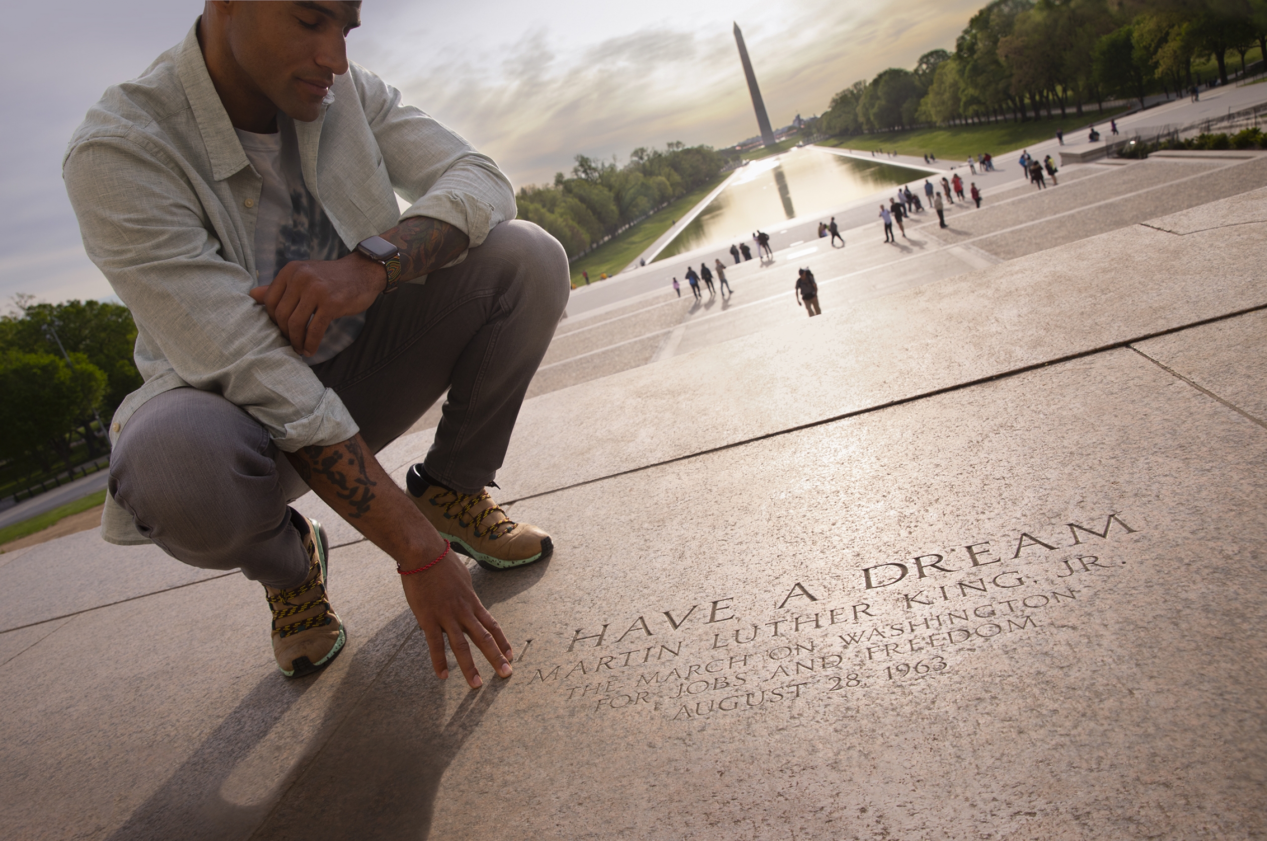 Man reading I Have a Dream inscription at the Lincoln Memorial with a view of the Washington Monument in the background.
