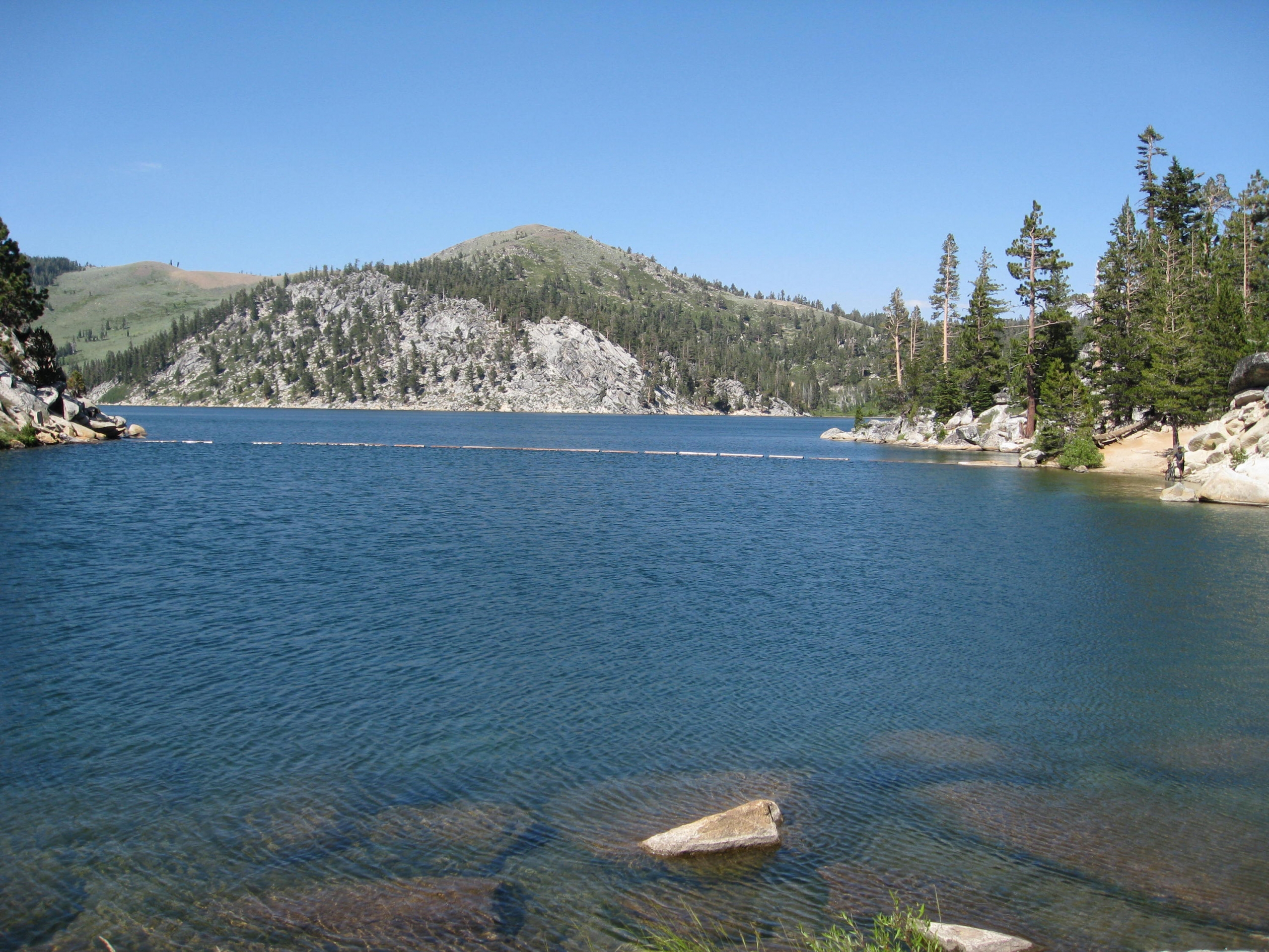 View across a blue lake sounded by grey granite mountains with evergreens at Marlette Lake along the Tahoe Rim Trail