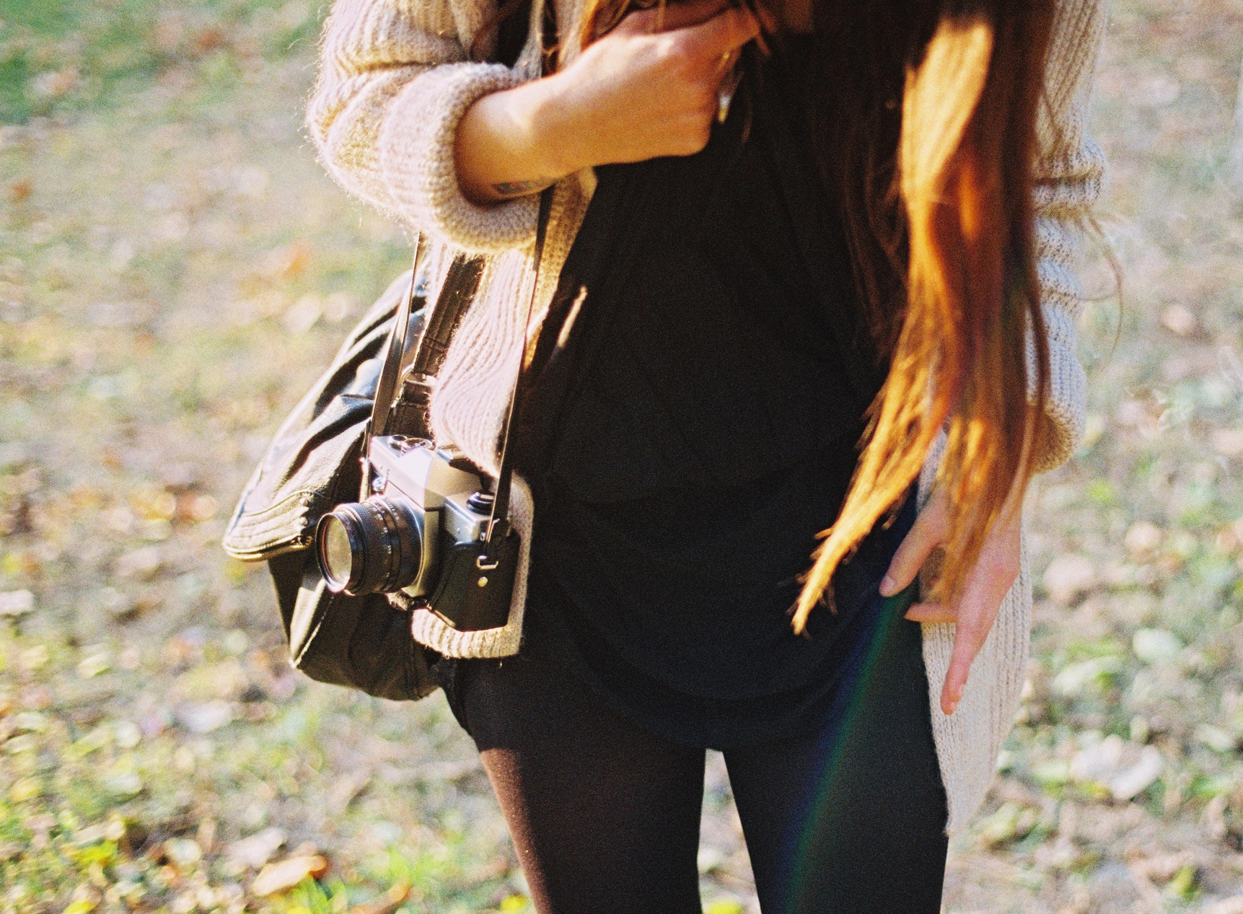 Woman holding a camera walking in a field 