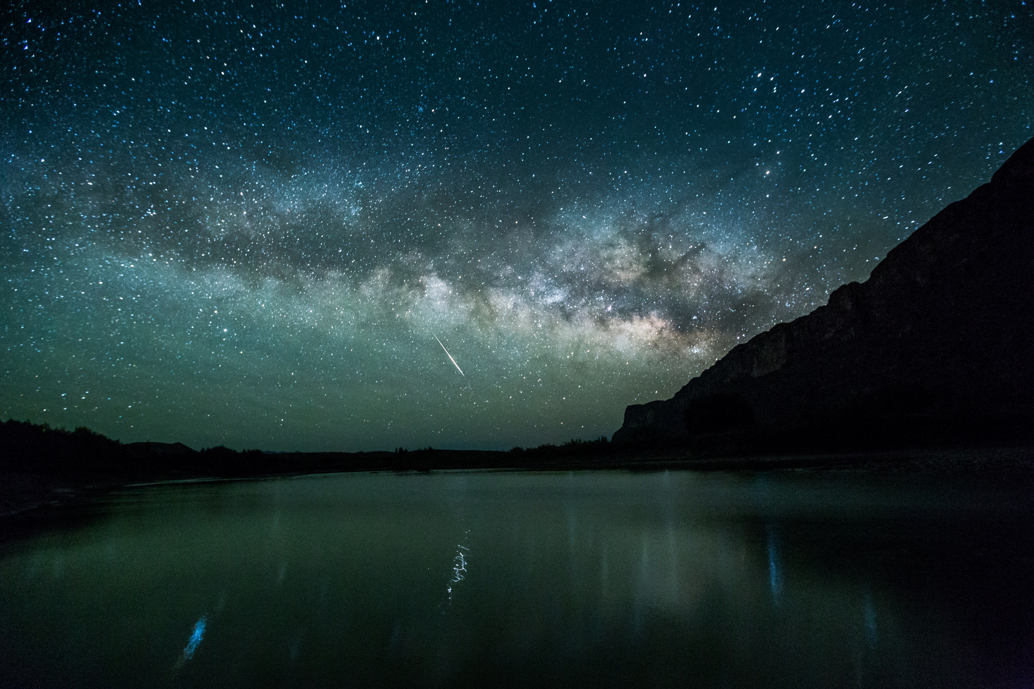 Vía Láctea verde-azul con un meteoro sobre un lago en el Cañón de Santa Elena en el Parque Nacional Big Bend