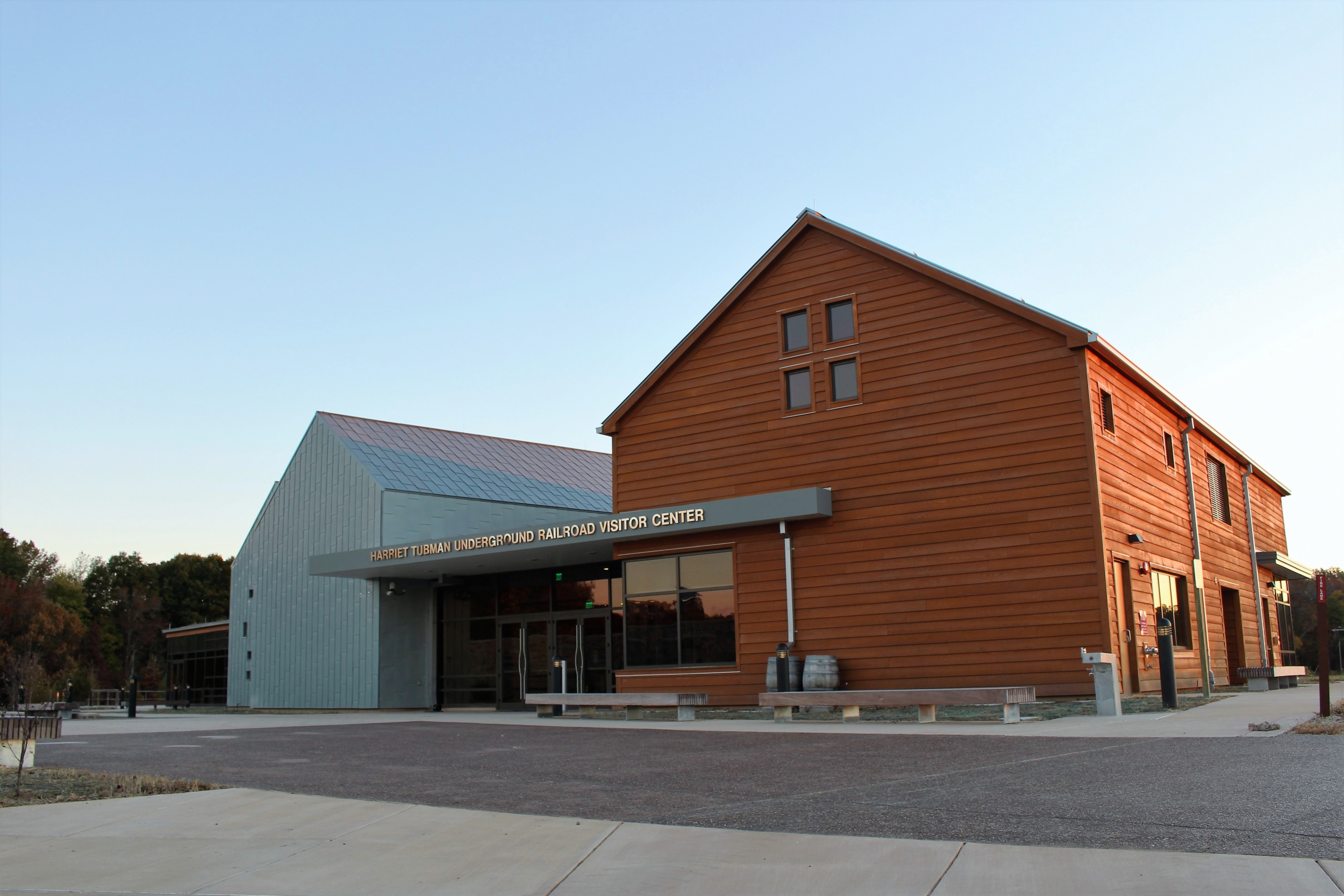 Front view of the visitor center, with two barn-like fronts visible, one in orange wood panel and one in metallic gray.