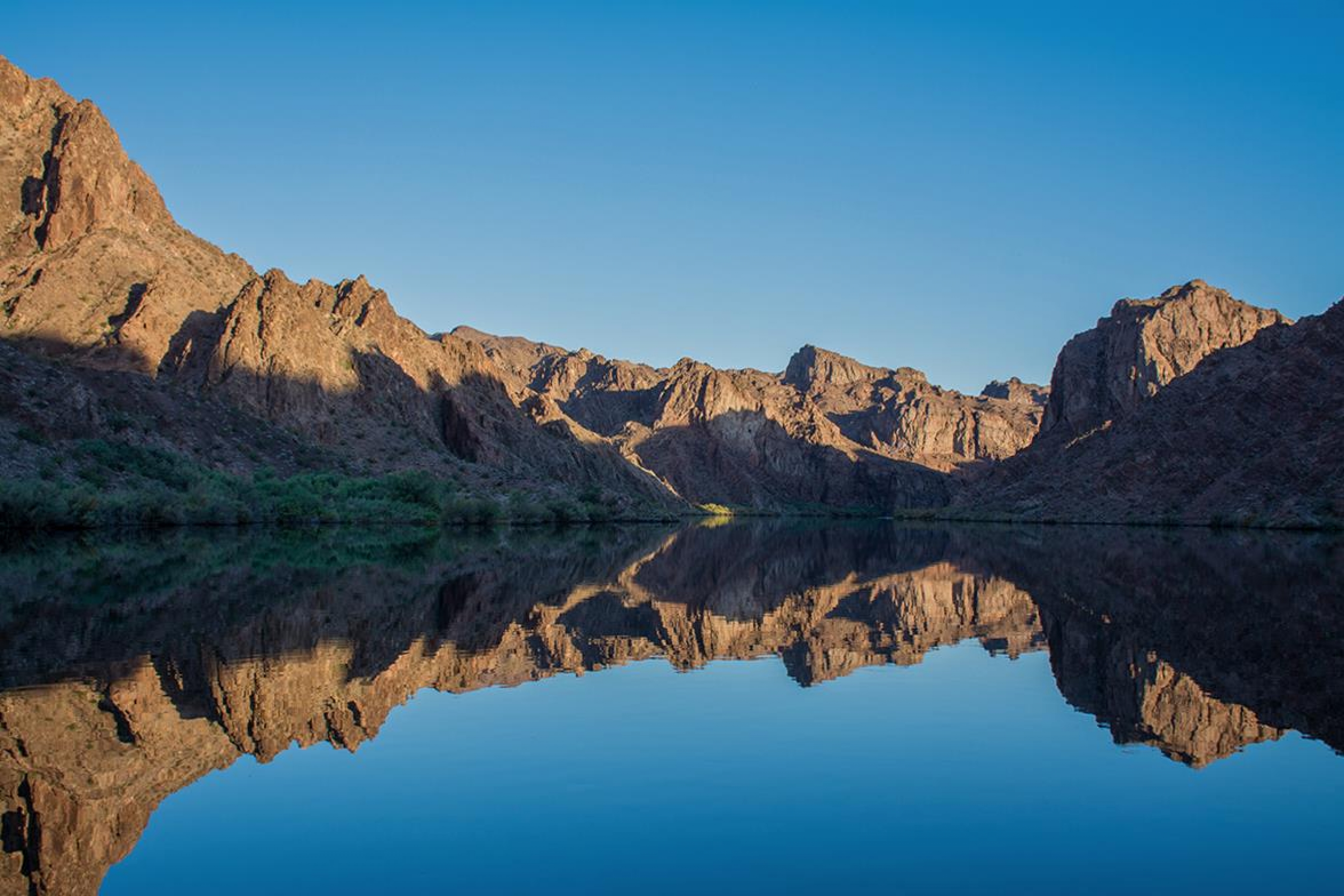 The red sandstone canyon walls reflecting in the still waters of the Black Canyon Water Trail at Lake Mead National Recreation Area
