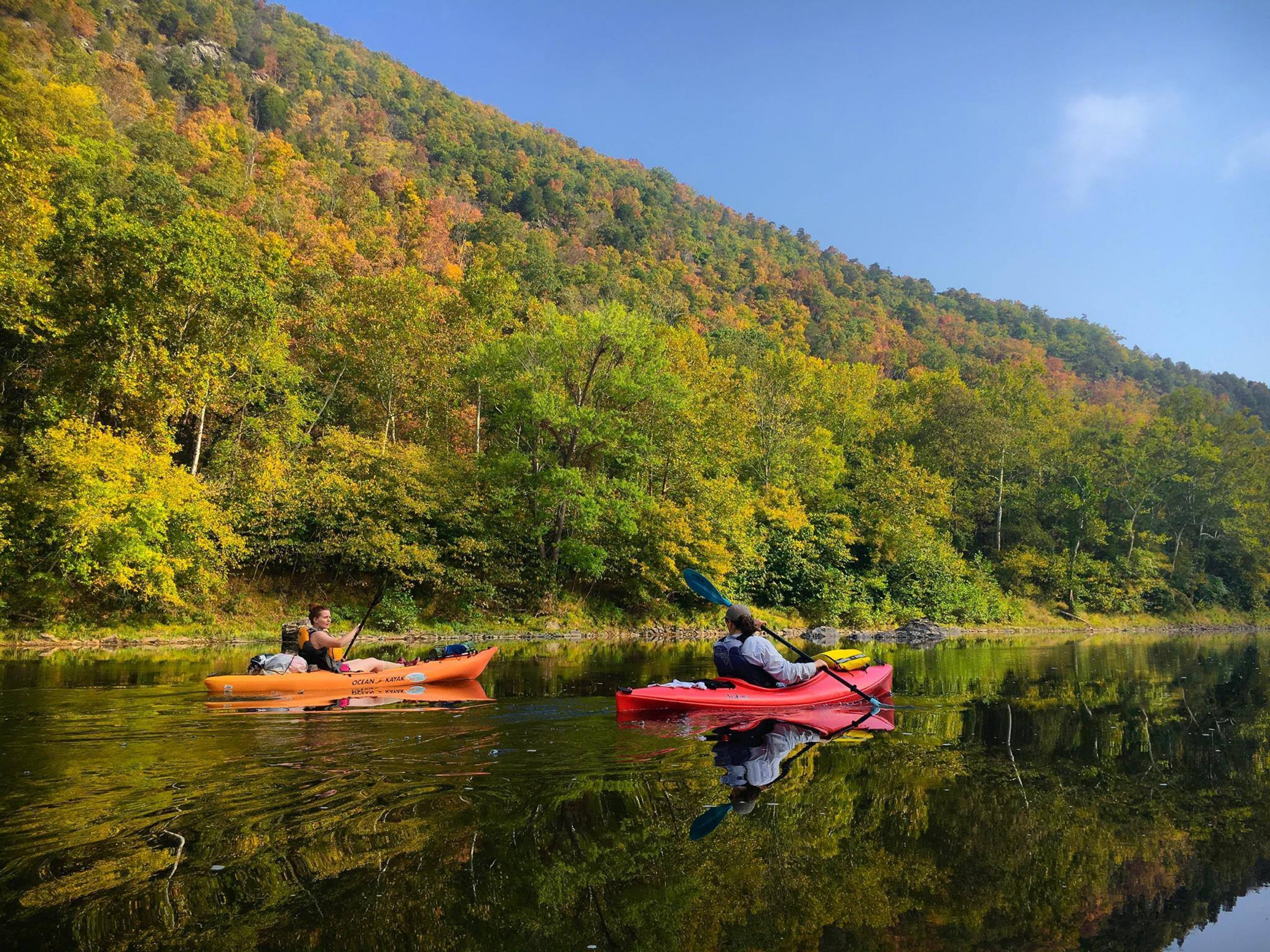 Dos kayakistas remando por el río Potomac bordeado de árboles de otoño a lo largo del sendero escénico nacional Potomac Heritage