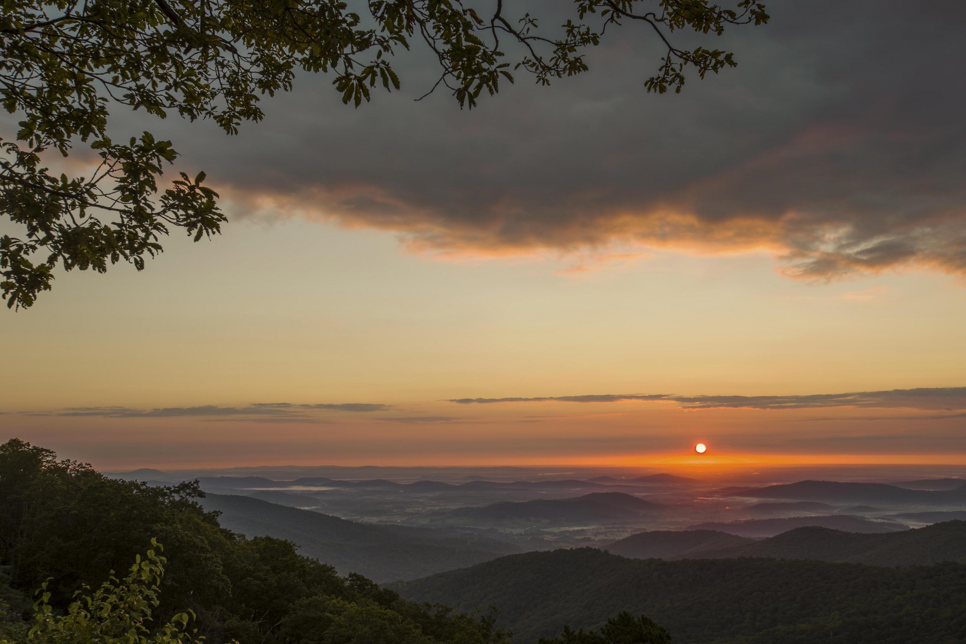 Orange sun rising over the misty valley from Hazel Mountain Overlook at Shenandoah National Park