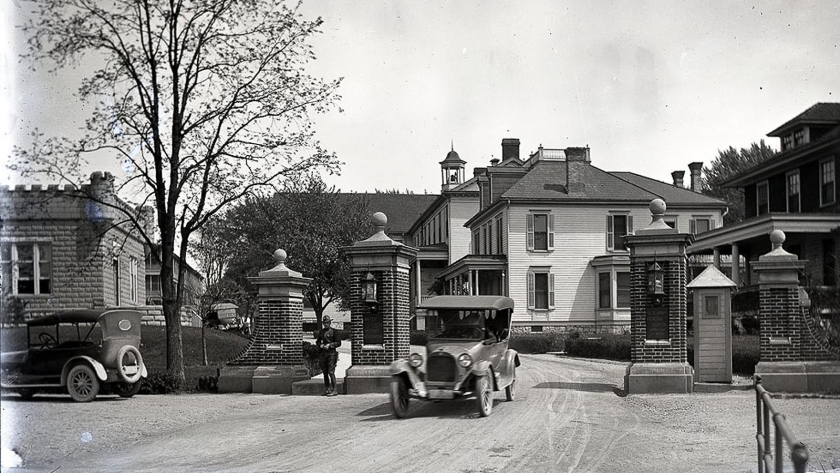 Historic image of Carlisle Federal Indian Boarding School and several cars on the road outside the building