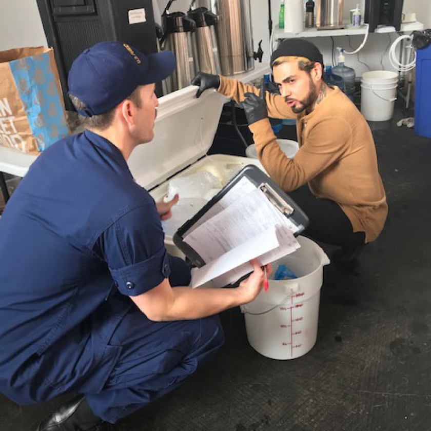 Lieutenant Commander Matt Kozler speaking with a food vendor before the COVID-19 pandemic