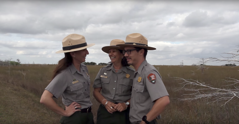 Three park rangers chatting and laughing in the middle of the prairie