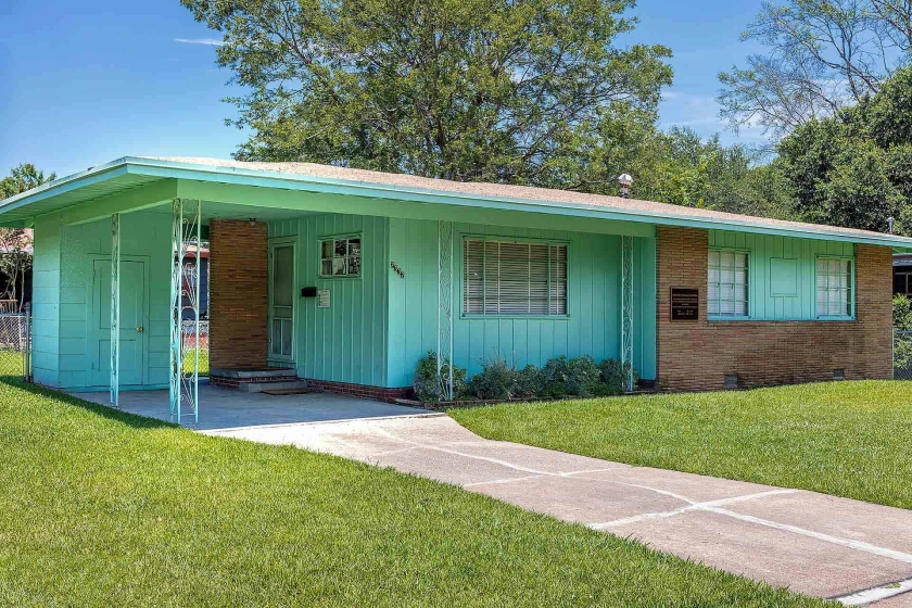 Una casa estilo rancho de un solo piso con ladrillo marrón claro y revestimiento verde azulado.