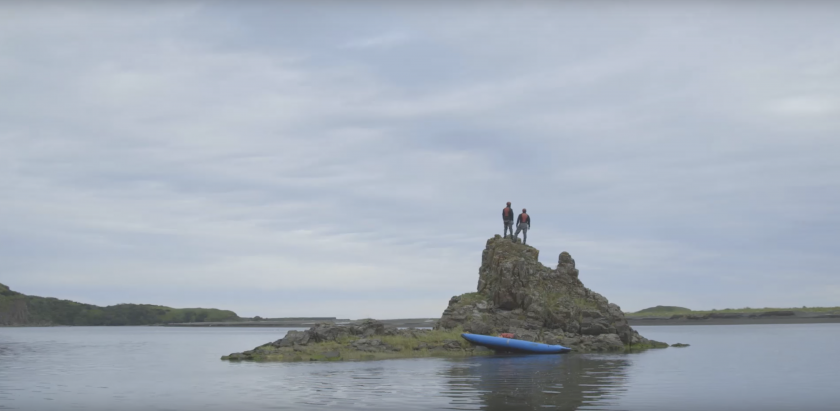 Two guys standing on a rock island