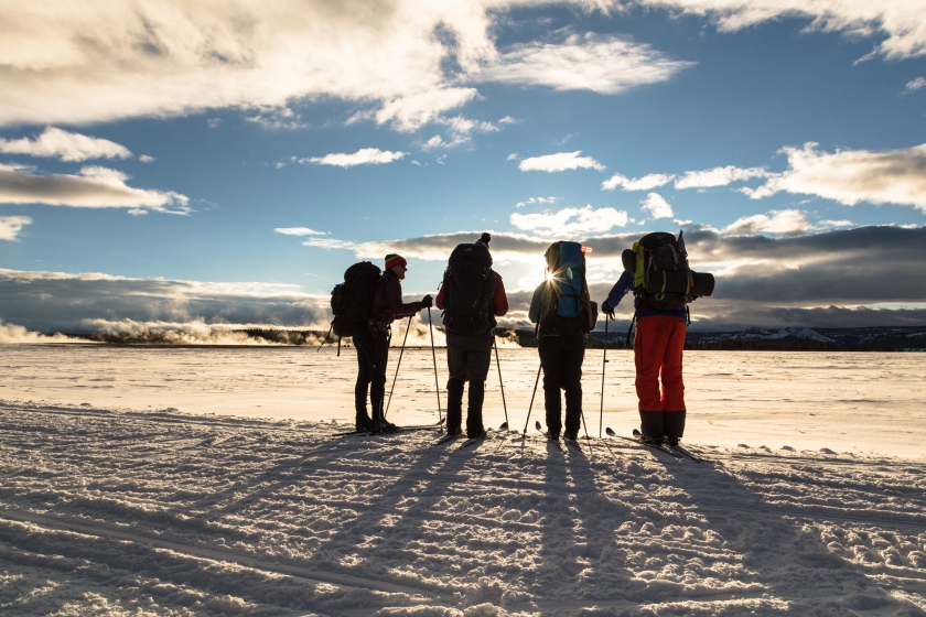 4 Backcountry skiers watching the sunset across the Lower Geyser Basin at Yellowstone National Park